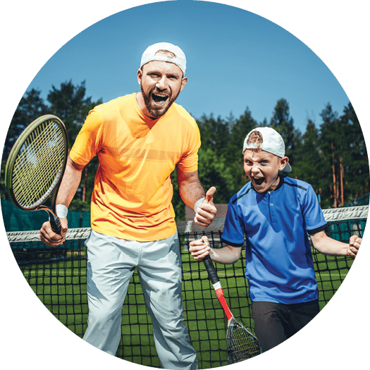 Portrait of shouting positive man and cheerful kid gesticulating hands while looking at camera. They holding rackets and standing on court for playing tennis outdoor