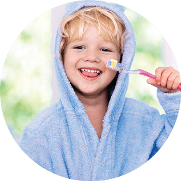 Child brushing teeth. Kids tooth brush and paste. Little baby boy in blue bath robe or towel brushing his teeth in white bathroom with window on sunny morning. Dental hygiene and heath for children.